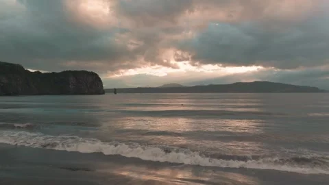 Dramatic sunset over calm ocean waves and rocky coastline at dusk Stock Footage 336295390