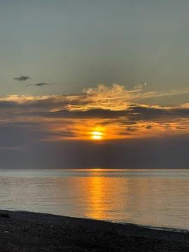 Dramatic sunset over calm ocean with glowing clouds Stock Photos