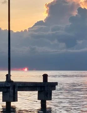 Dramatic Sunset Over Calm Ocean with Large Dark Clouds. Stock Photos