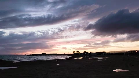 Dramatic sunset over a calm sandy beach with purple and orange clouds. Stock Footage 329512560