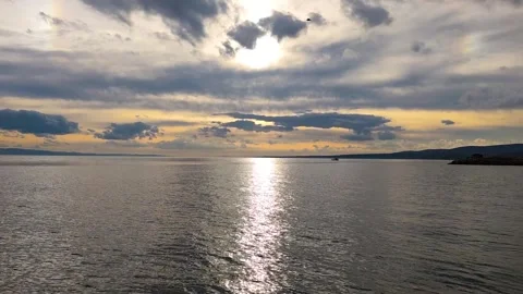 Dramatic Sunset over Calm Sea with Golden Light Reflection and Dark Clouds Stock Footage 330756362