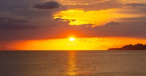 Dramatic Sunset Over Calm Water With Colorful Evening Sky Stock Photos