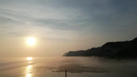 Dramatic Sunset Over Coastal Cliffs with Golden Mist Stock Footage 315504332