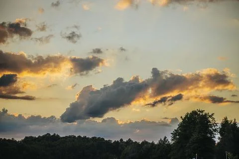 Dramatic sunset over a forested landscape with vibrant clouds and warm hues.. Foto stock