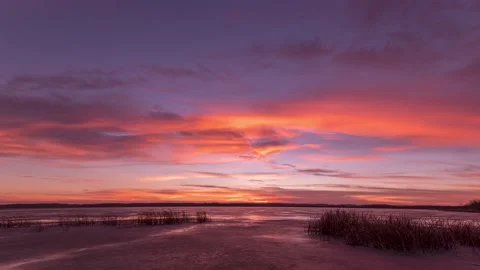 Dramatic sunset over a frozen beaver pond with reeds in foreground. Stock Footage 142596723