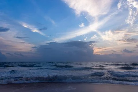 Dramatic sunset over the Indian Ocean with crashing waves on a sandy beach Stock Photos