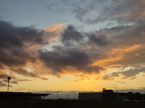 Dramatic sunset over industrial skyline with storm clouds Stock Photos