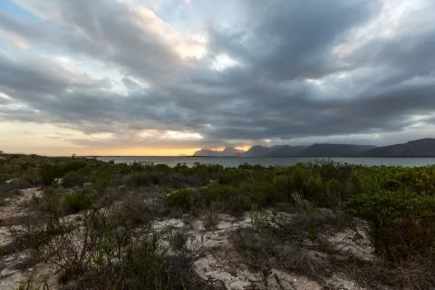 Dramatic sunset over lake and mountain range under dramatic clouds Stock Photos
