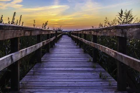 Dramatic Sunset over Lake and Wooden Walkway with Railing Stock-Fotos