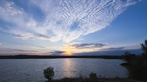 Dramatic sunset over a lake beneath a textured cloudscape Stockfoto's