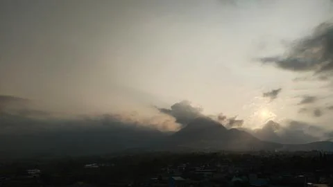 Dramatic Sunset Over Misty Mountains and Town with Sunbeams Stock Photos