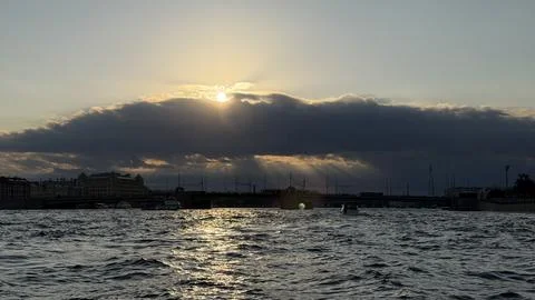 Dramatic sunset over the Neva River. Sunbeams pierce through heavy dark clouds Stock Photos