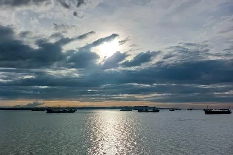 Dramatic Sunset Over Ocean with Cargo Ship Silhouettes. Stock Photos