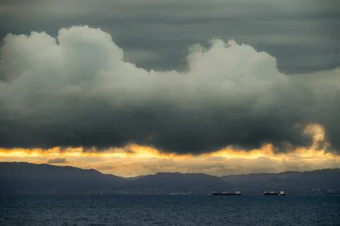 Dramatic sunset over the ocean with clouds and distant ships Photos