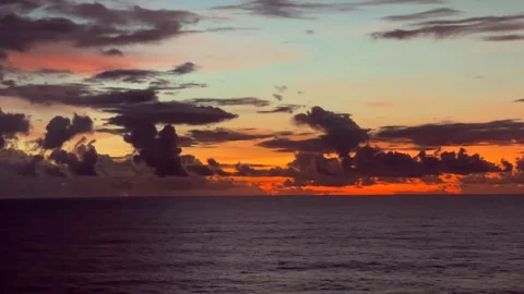 Dramatic sunset over the ocean with colorful clouds and calm water 動画素材 338282747