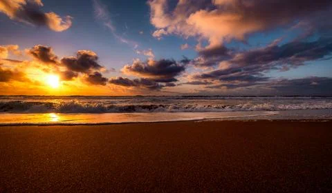 Dramatic sunset over the ocean with colorful clouds and crashing waves 스톡 사진