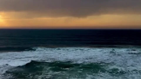 Dramatic sunset over the ocean with dark storm clouds and rolling waves Vidéo 334084884