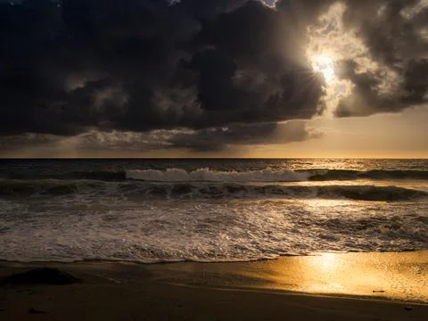 Dramatic sunset over the ocean with dark clouds and golden light reflecting.. Foto stock