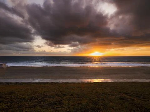 Dramatic sunset over the ocean with dark clouds and golden light rays Fotos de archivo