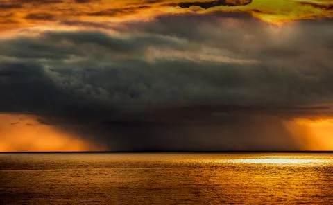 Dramatic sunset over the ocean with dark storm clouds and golden light Foto stock