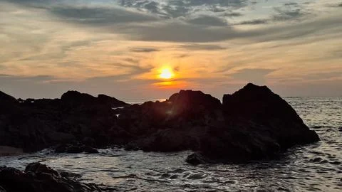 Dramatic Sunset Over Ocean with Dark Rocky Beach Silhouette Stock Photos