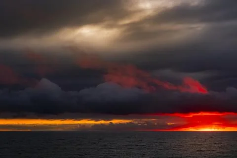 Dramatic sunset over the ocean with fiery red and orange clouds Fotos de archivo