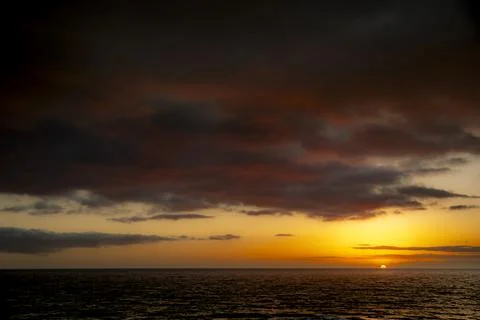 Dramatic sunset over the ocean with fiery clouds and calm water Fotos de archivo