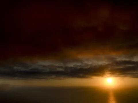 Dramatic sunset over the ocean with fiery clouds and shimmering reflection 스톡 사진