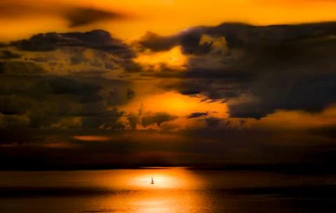Dramatic sunset over the ocean with a lone sailboat on the horizon Foto stock