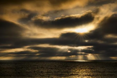Dramatic sunset over the ocean with rays shining through clouds Fotos de archivo