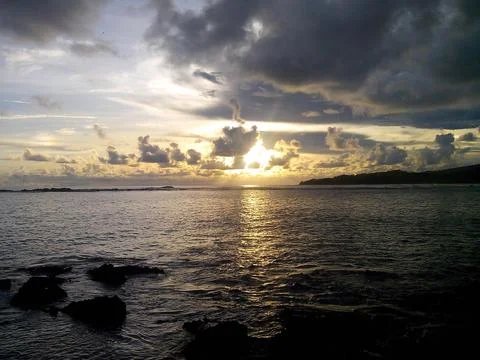 Dramatic Sunset Over the Ocean with Silhouetted Coastline and Clouds Foto stock
