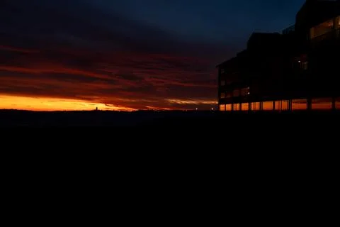 Dramatic sunset over the ocean with a silhouetted building reflecting the f.. Fotos de archivo