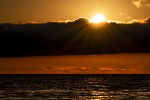 Dramatic sunset over the ocean with sun rays and dark clouds Fotos de archivo