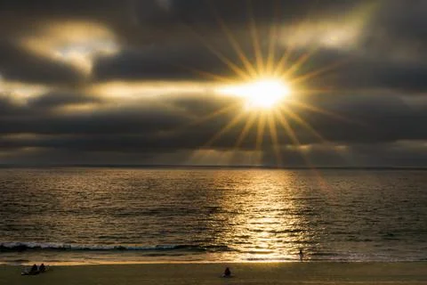Dramatic sunset over the ocean with sun rays breaking through dark clouds Fotos de archivo