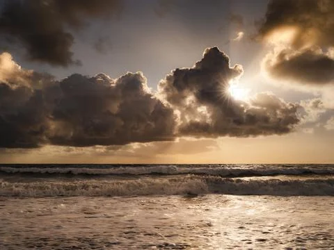 Dramatic sunset over the ocean with sunbeams breaking through dark clouds Fotos de archivo