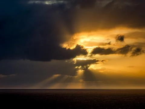 Dramatic sunset over the ocean with sunbeams breaking through dark clouds Foto stock