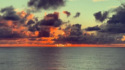 Dramatic sunset over ocean with vibrant clouds reflecting warm colors on th.. Stock Footage 338282020