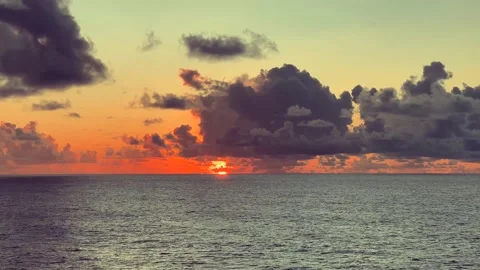 Dramatic sunset over the ocean with vibrant orange sky and dark clouds crea.. Stock Footage 338282065