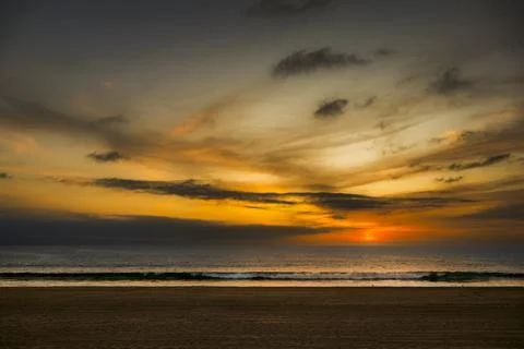 Dramatic sunset over the ocean with vibrant orange and yellow clouds illumi.. Fotos de archivo