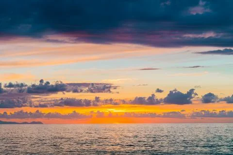 Dramatic sunset over the ocean with vibrant orange and purple clouds Stock Photos