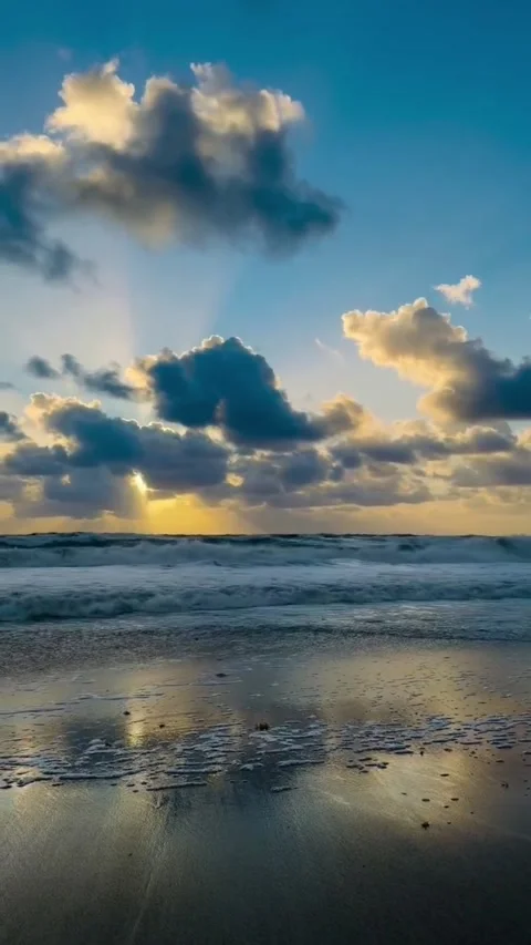 Dramatic sunset over ocean waves with sun rays piercing through clouds Vidéo 334084897