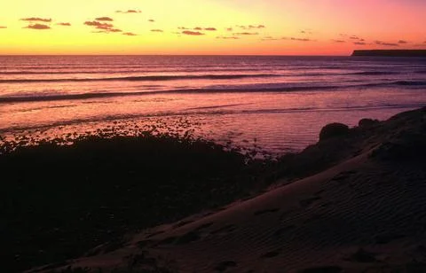 Dramatic Sunset Over Ocean Waves and Sandy Coast Stock Photos