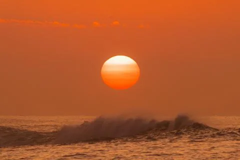 Dramatic Sunset Over Ocean Waves with Fiery Orange Sky Stock Photos