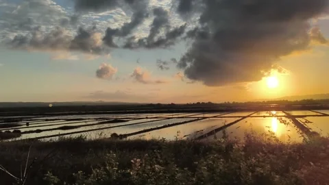 Dramatic Sunset Over Salt Ponds with Reflective Water and Stormy Clouds Stock Footage 340465198