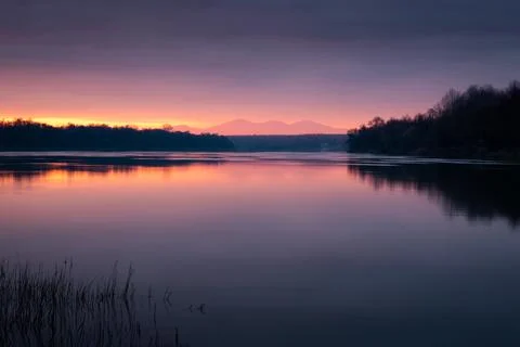 Dramatic sunset over Sava river with mountain in hazy glow Stock Photos