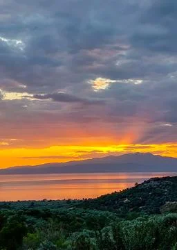 Dramatic sunset over the sea and mountain silhouette Stock Photos