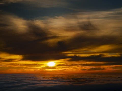 Dramatic sunset over a sea of clouds with vibrant orange and yellow hues 库存照片