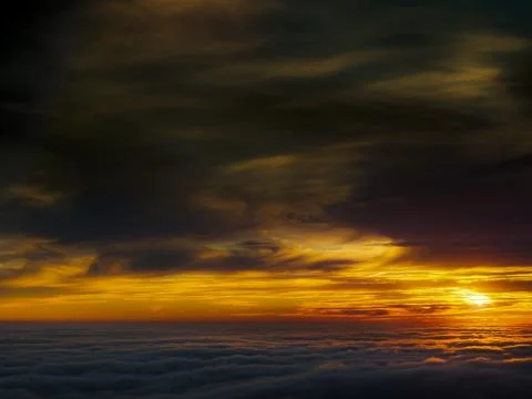 Dramatic sunset over a sea of clouds with fiery orange and dark stormy skies Fotos de archivo