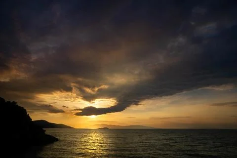 Dramatic Sunset Over Sea with Dark Clouds and Golden Light Stock Photos
