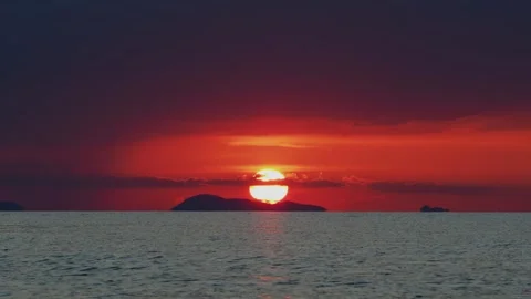 Dramatic sunset over sea, sun goes behind the an island on horizon Stock Footage 331340779